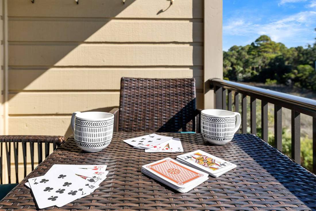 Balcony table set for cards with palm trees and ocean beyond